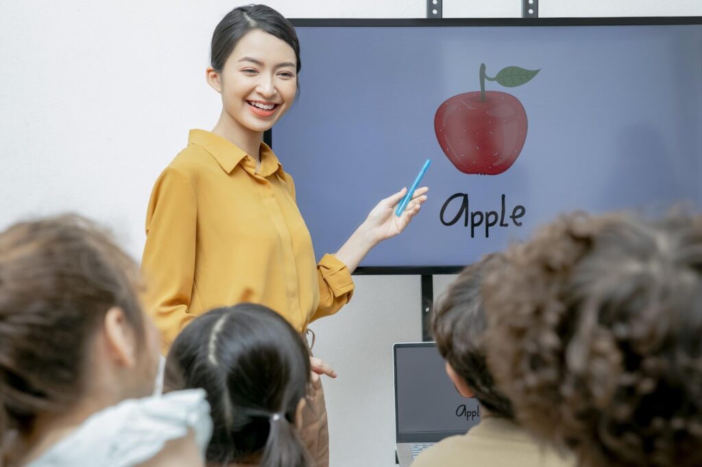 電子画面で英単語appleを教える女性教師
